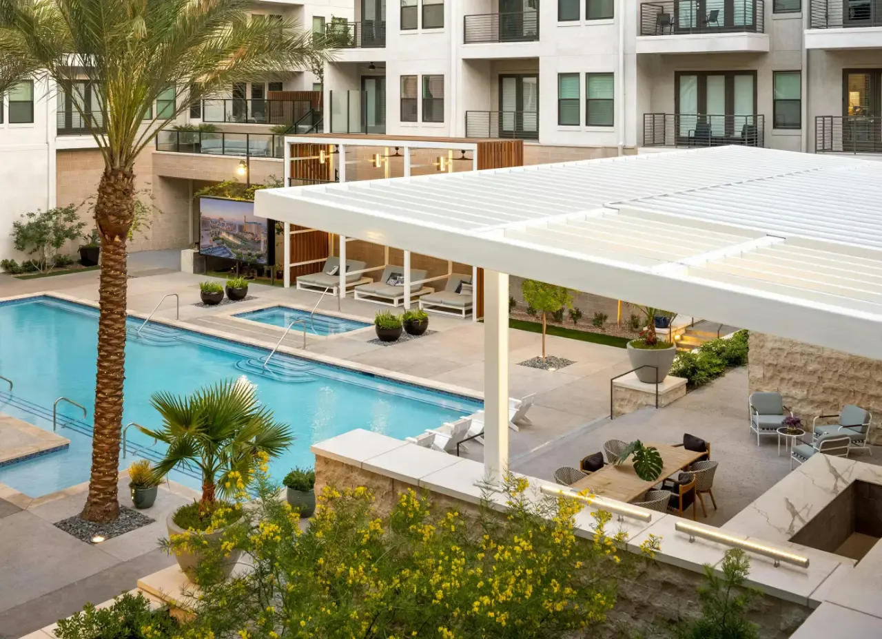 Pool and spa with shade structure, palm trees and apartment building at Auric at Symphony Park