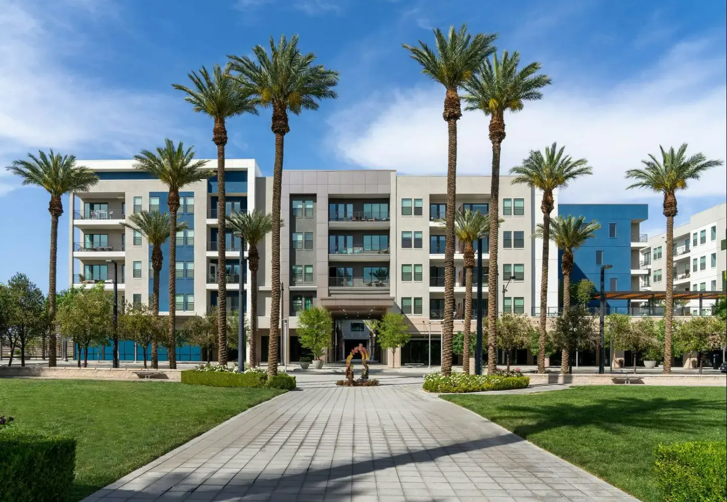 Apartment building and lawn framed by palm trees at Auric at Symphony Park