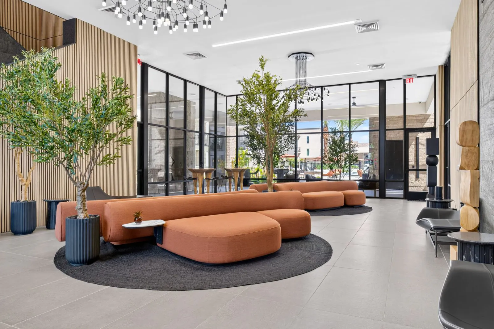 Lobby social lounge with orange sofas and potted trees at Harmony at Hawes Crossing