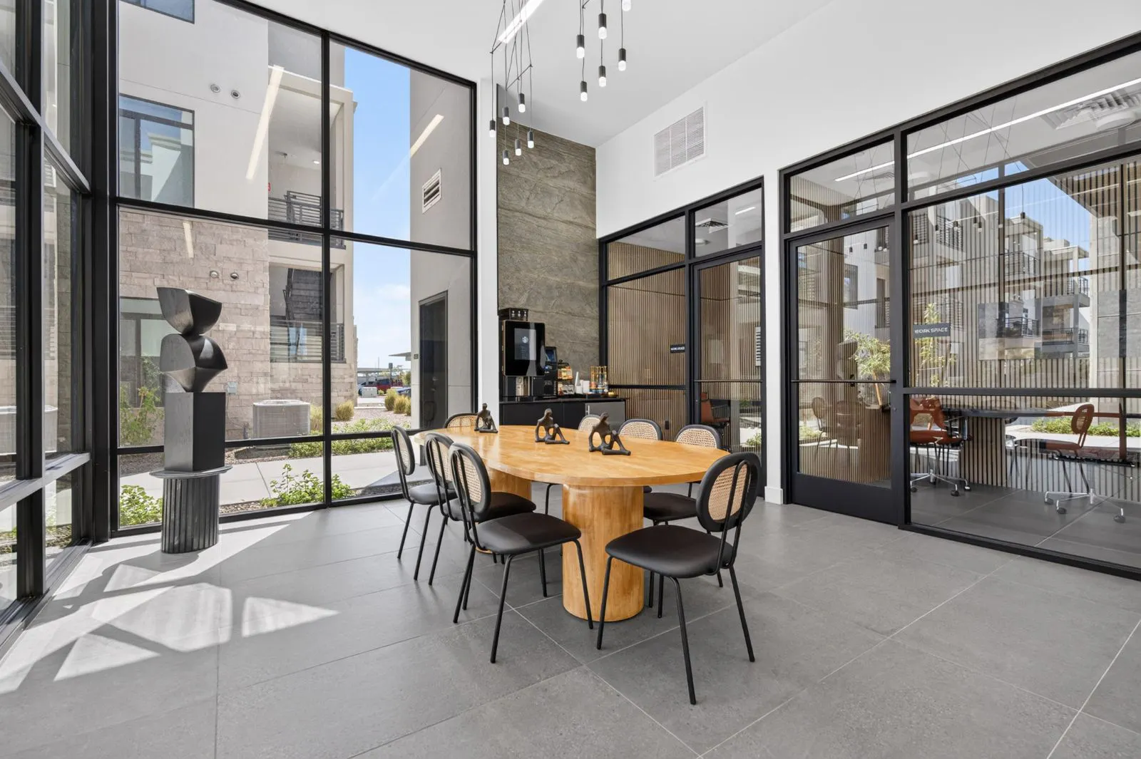 Coworking space with round wood table and floor-to-ceiling windows at Harmony at Hawes Crossing