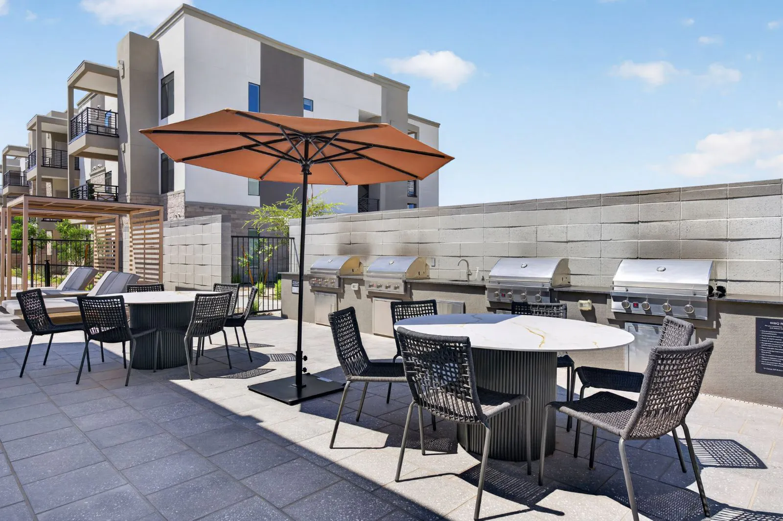 Outdoor grilling station with dining tables and umbrella at Harmony at Hawes Crossing