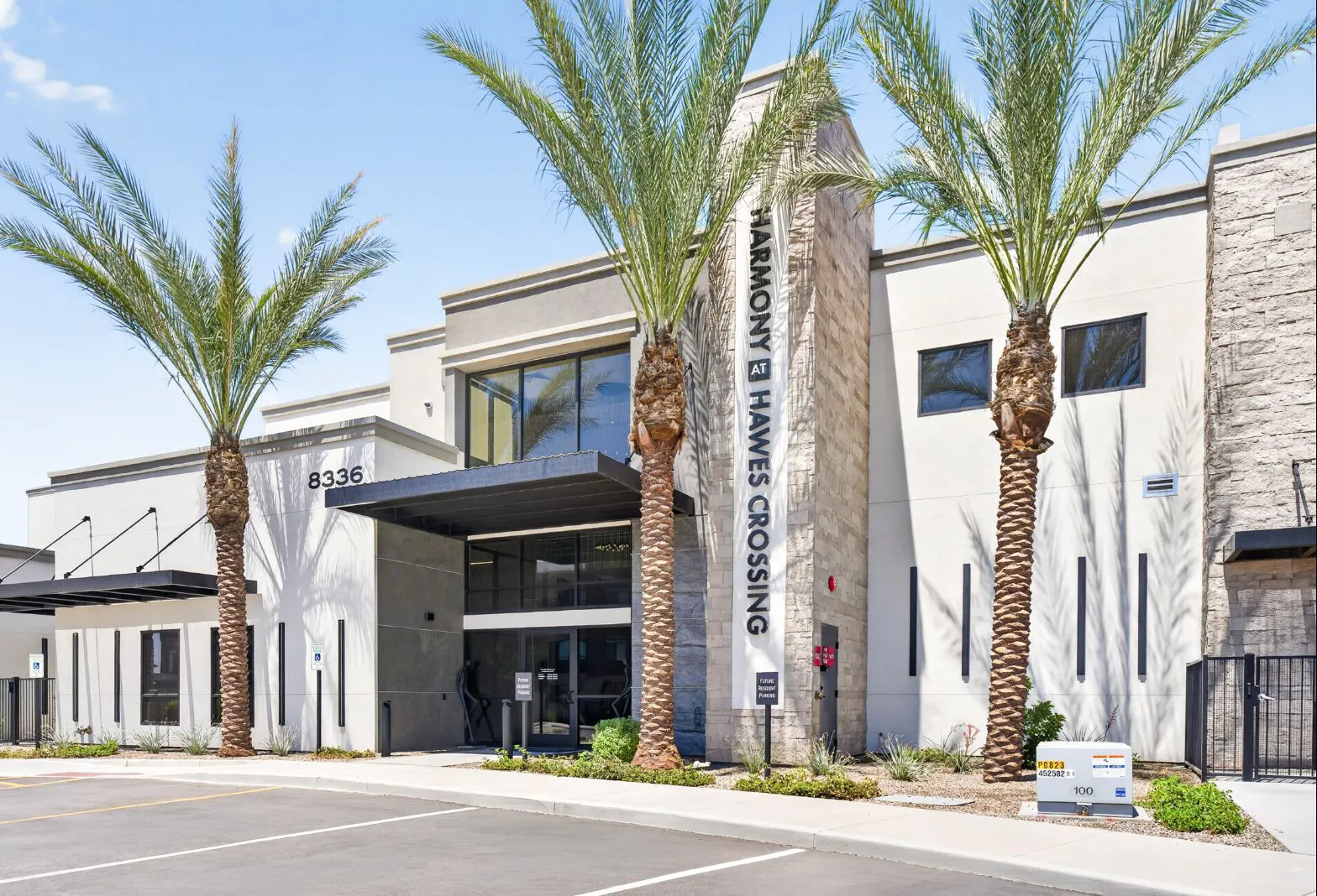Building entrance with palm trees and Harmony at Hawes Crossing signage