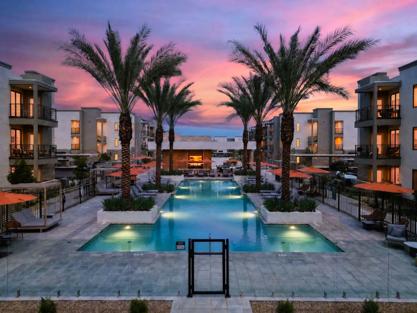 Pool and palm trees at sunset with lounge areas at Harmony at Hawes Crossing
