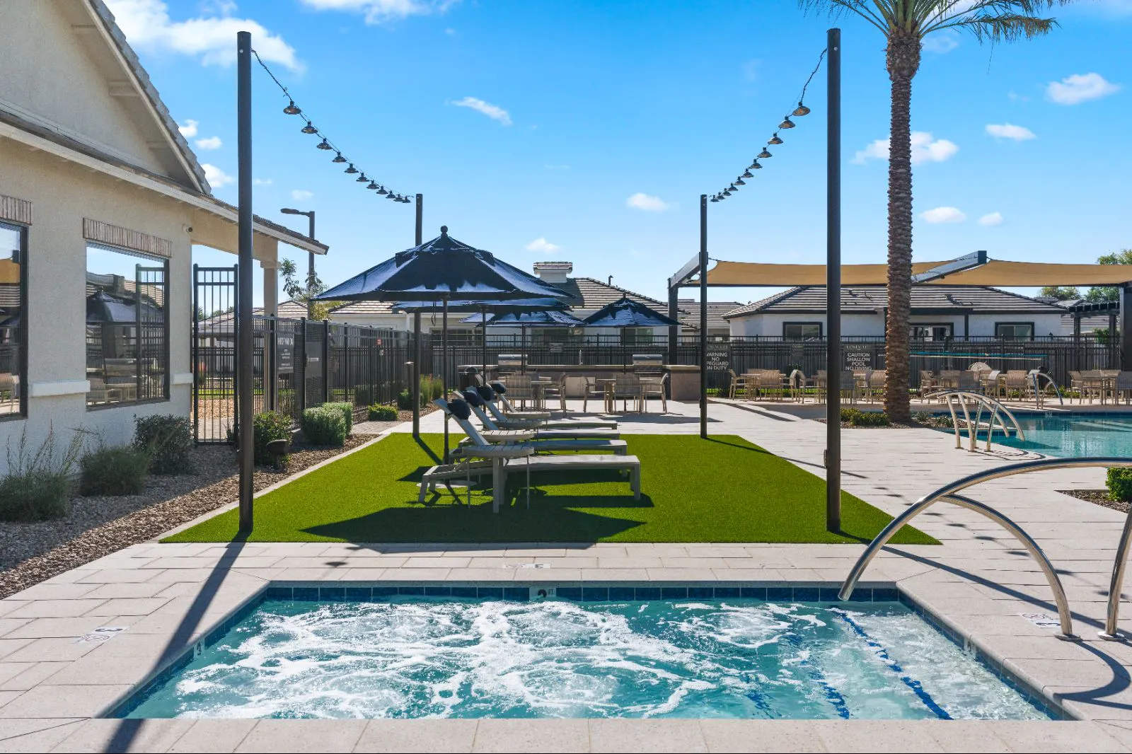 Spa with lounge chairs, umbrellas and string lights beside the pool at Honeycutt Run